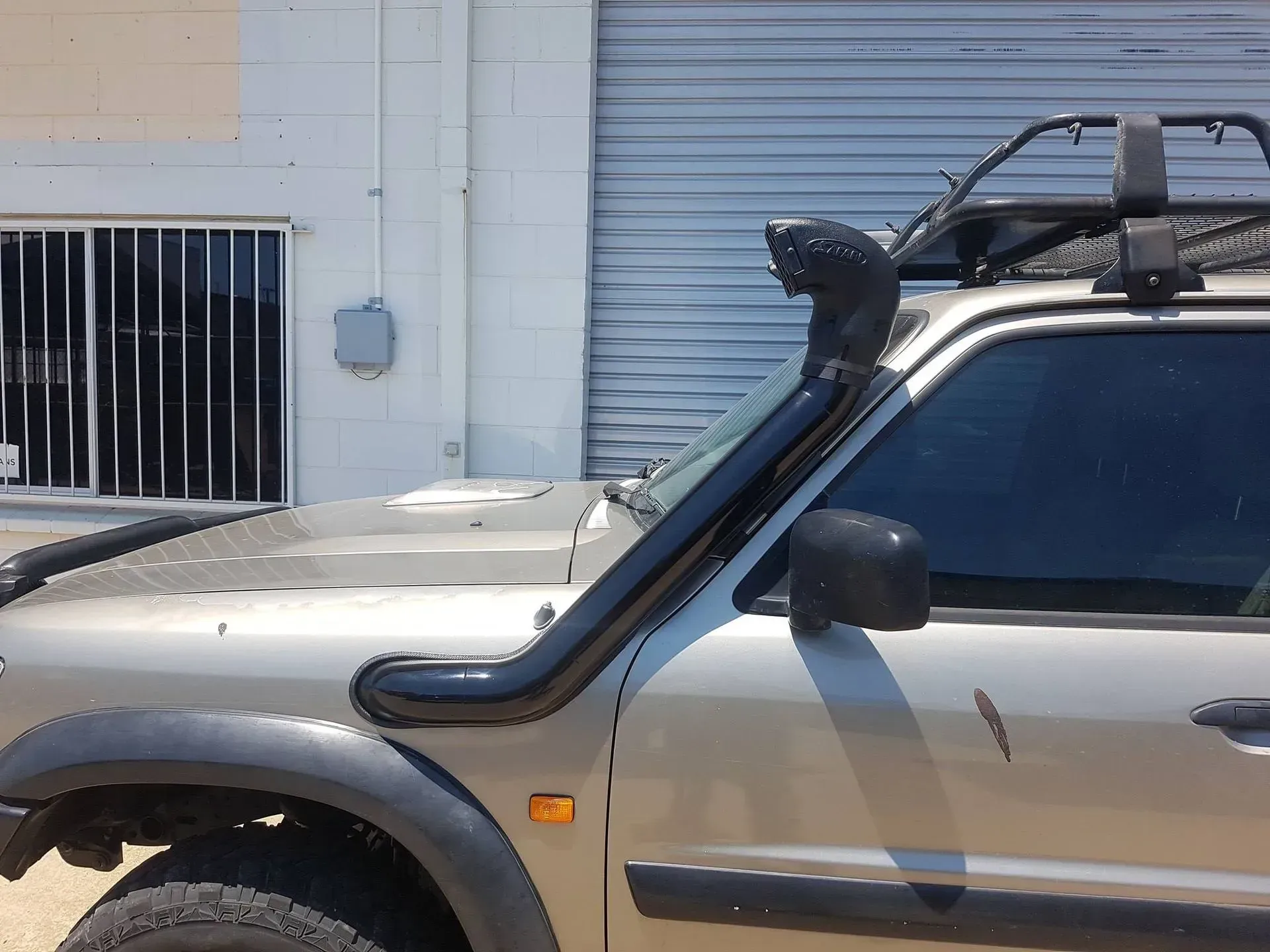 Beige SUV with snorkel parked beside a building with a closed roll-up door — Ironhide Customs In Garbutt, QLD