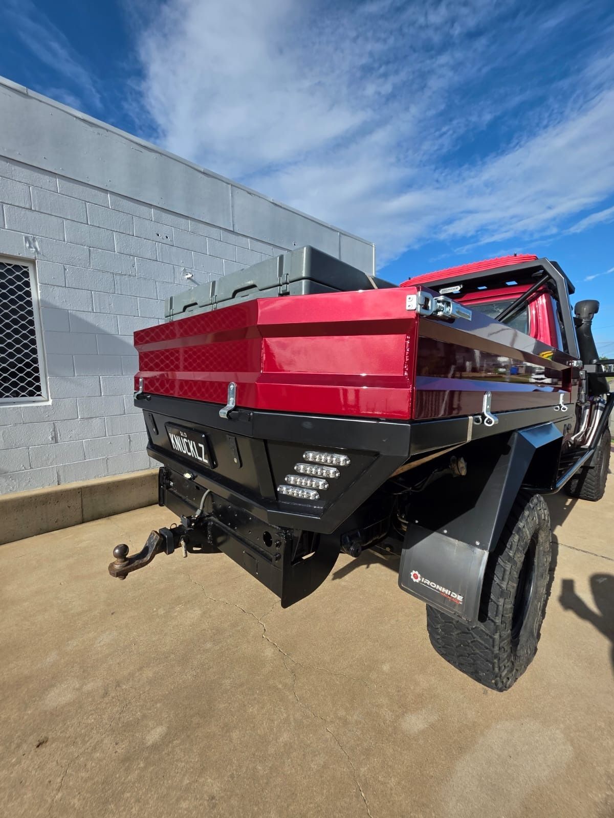 Red Flatbed Truck Parked Beside A Gray Building On A Sunny Day — Ironhide Customs In Garbutt, QLD