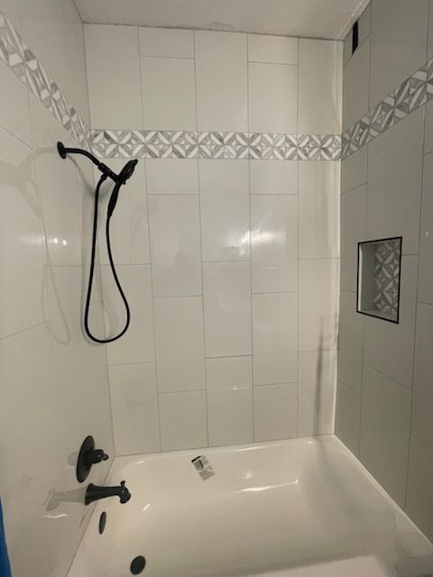 White tiled shower with black fixtures.