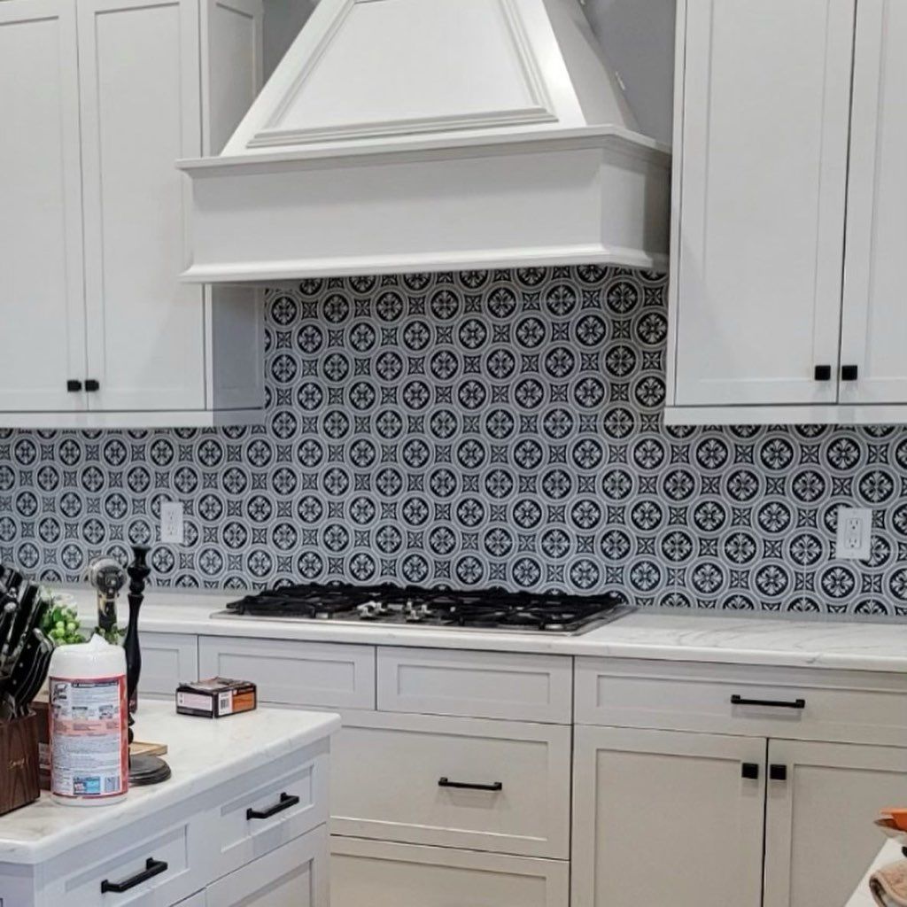 White kitchen with black and white patterned backsplash and cabinets.