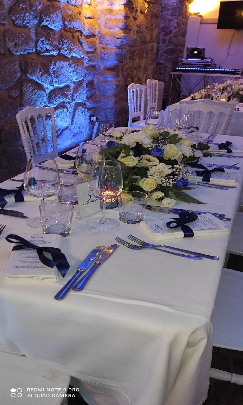 lungo tavolo con una tovaglia bianca e dei fiori sopra