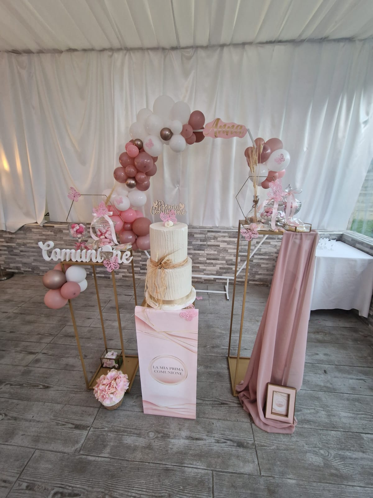 tavolo con una torta e un arco decorato con dei palloncini