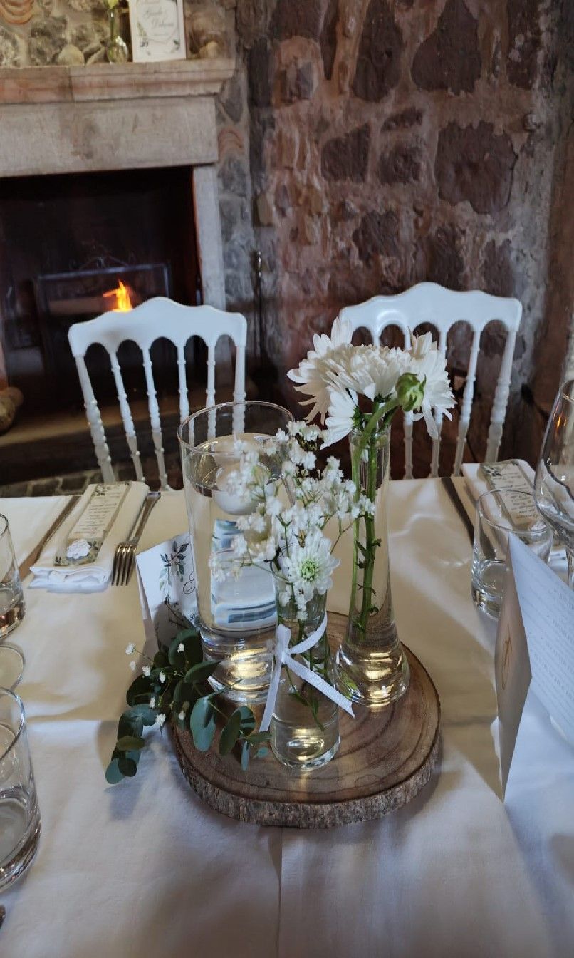 tavolo con un vaso di fiori sopra e un camino sullo sfondo