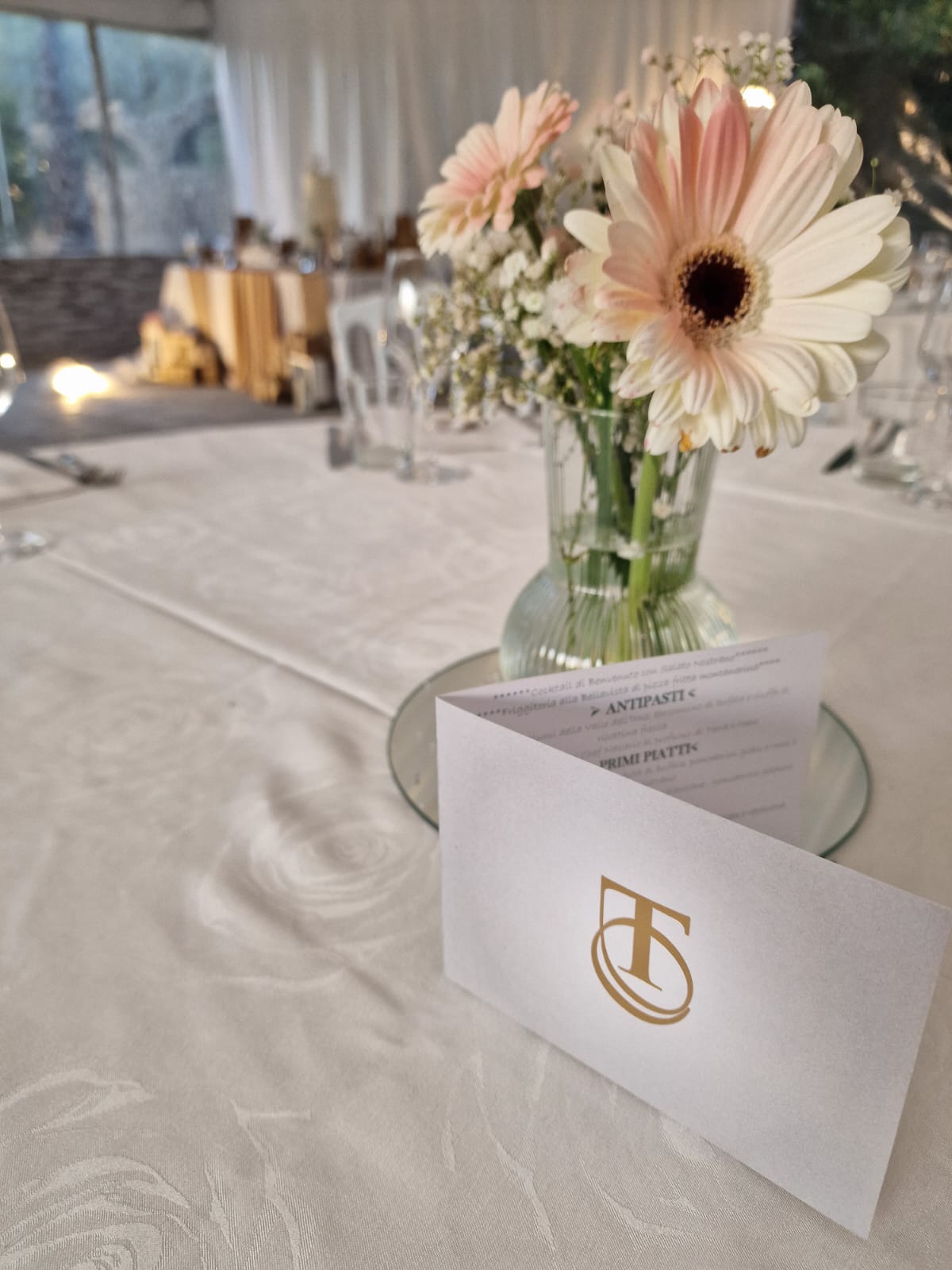 tavolo con un vaso di fiori e un segnaposto sopra