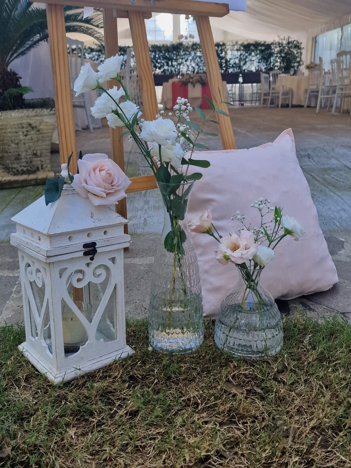 vaso di fiori è appoggiato sull'erba accanto a una lanterna