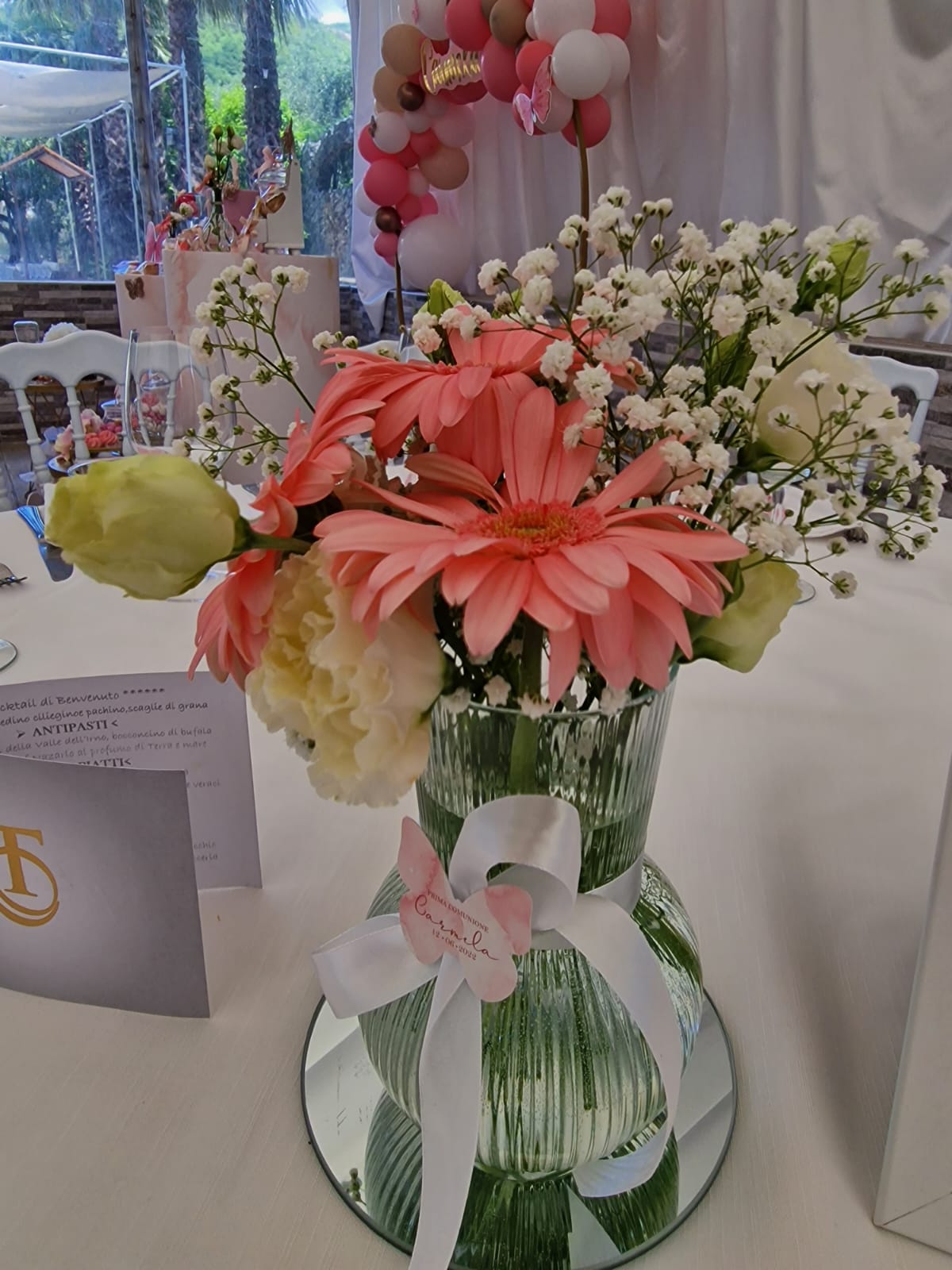 tavolo con un vaso pieno di fiori rosa e bianchi