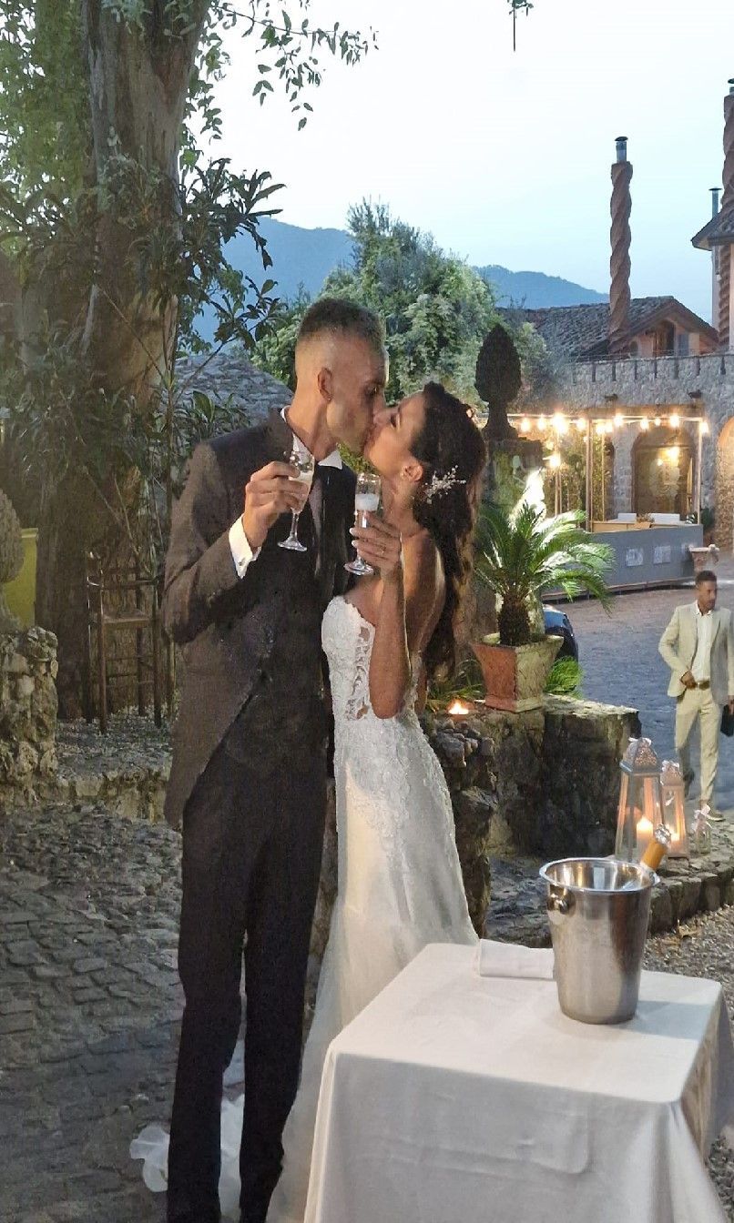 Una sposa e uno sposo che si baciano mentre tengono in mano dei bicchieri di champagne