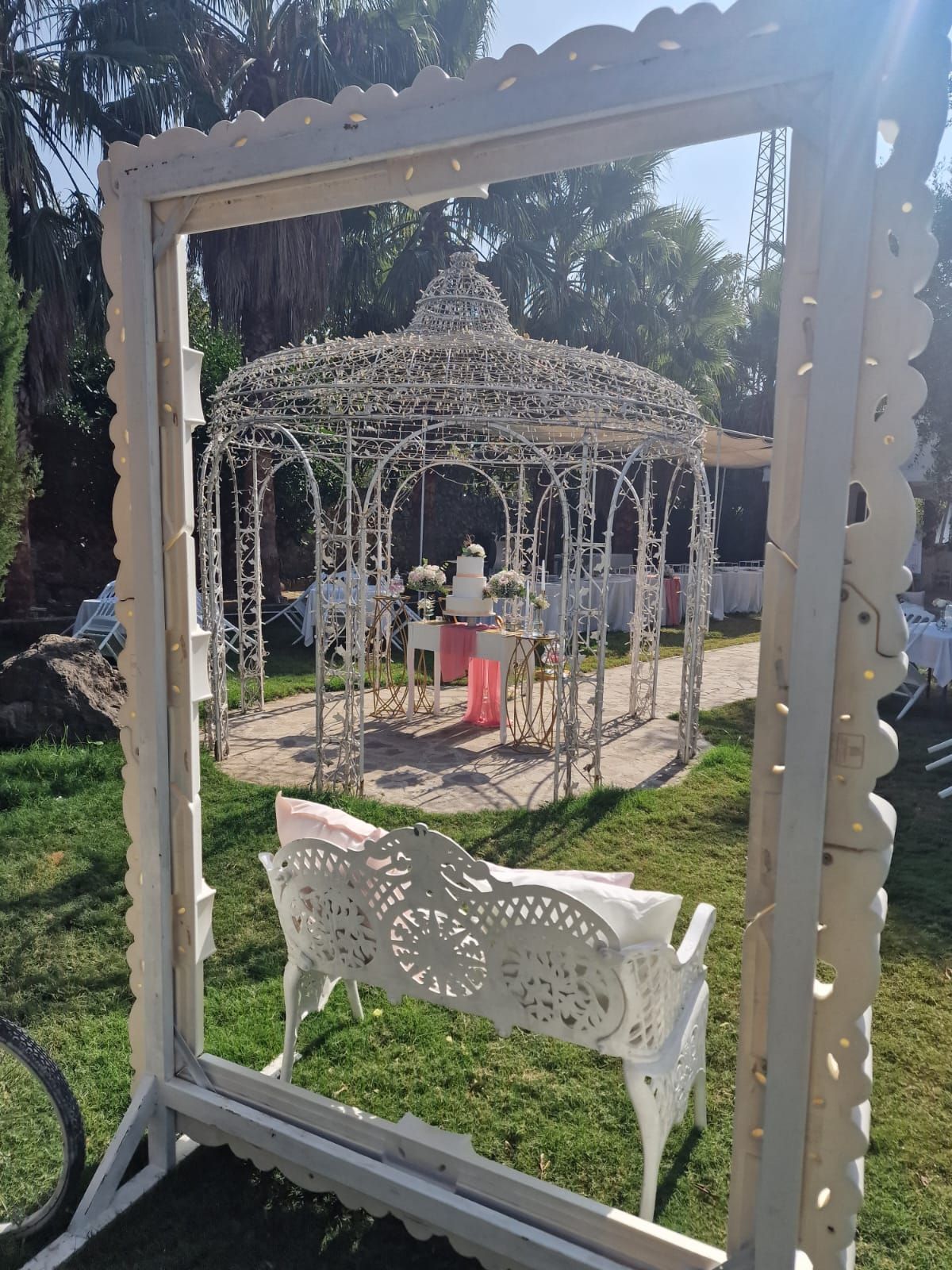 cornice bianca appoggiata sull'erba davanti a un gazebo.