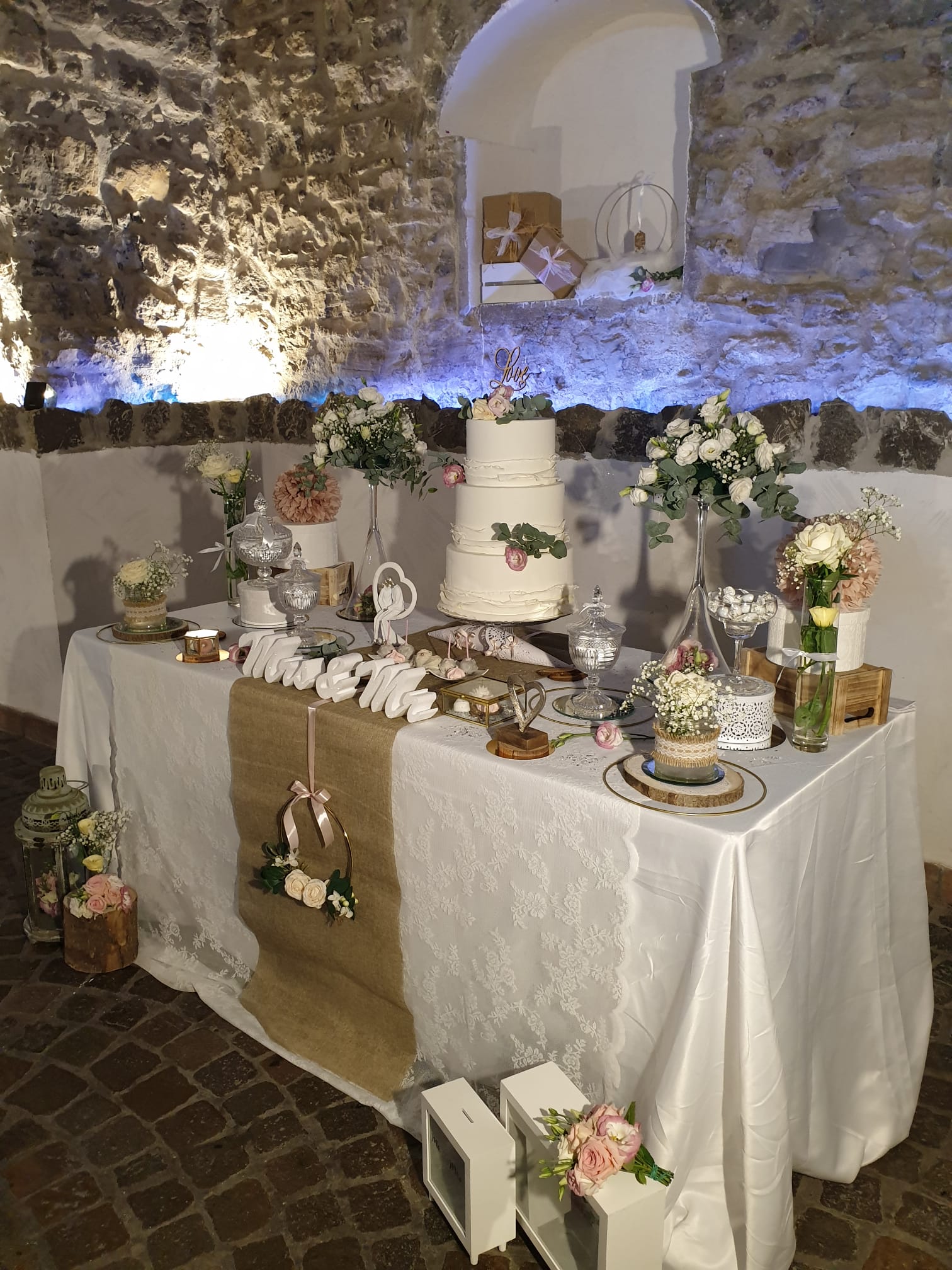 tavolo con una torta e dei fiori sopra in una  sala per ricevimenti