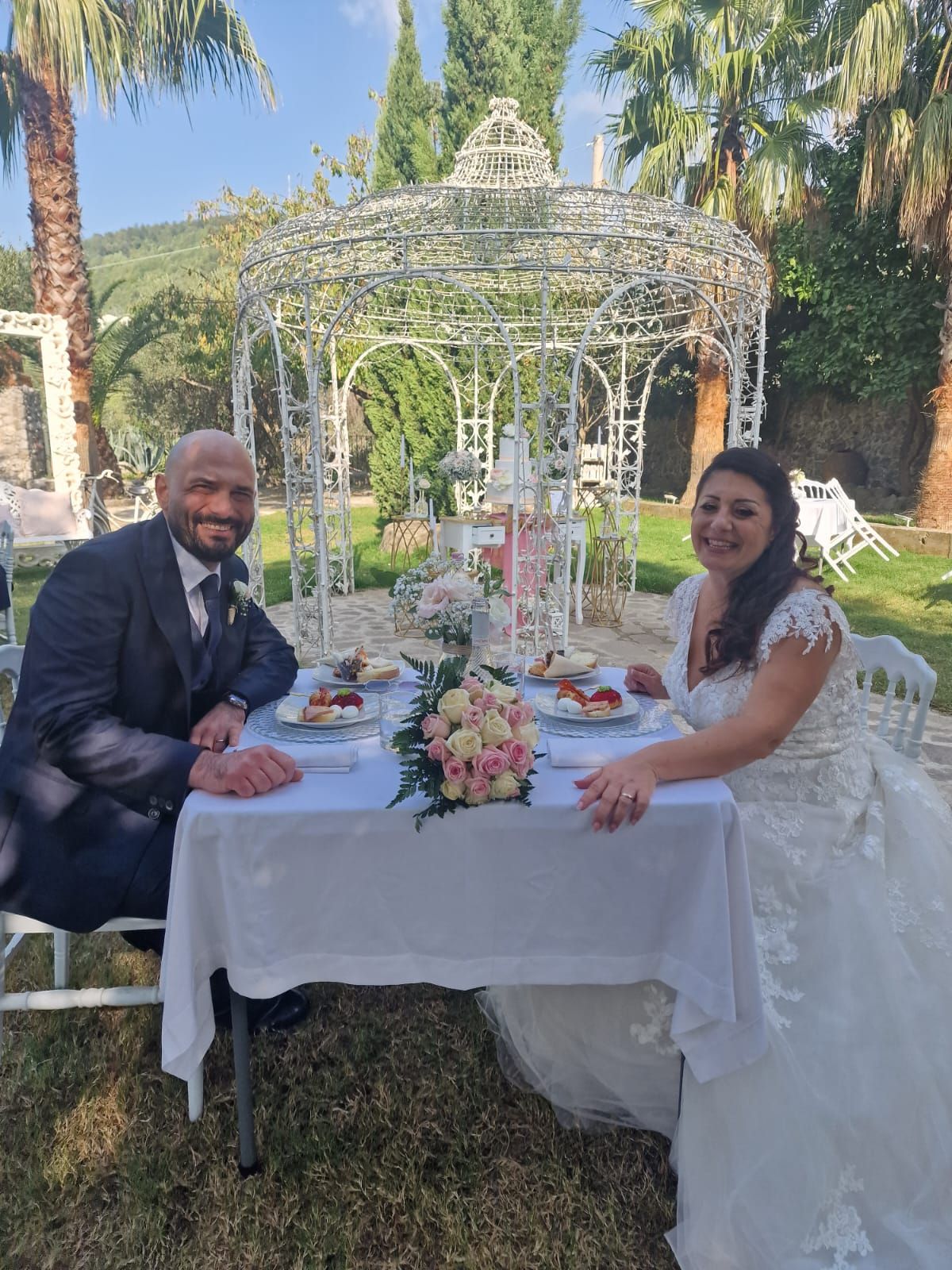 sposi sono seduti a un tavolo davanti a un gazebo.