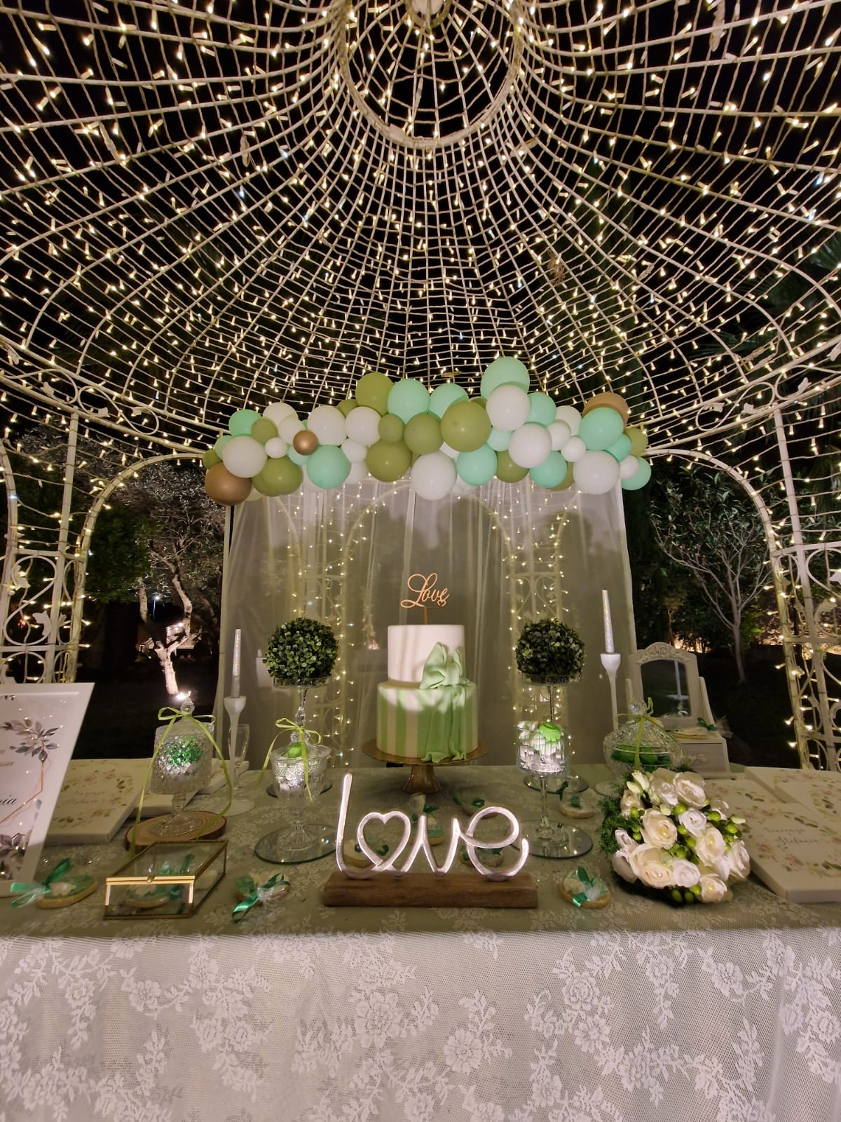 tavolo con una torta e dei palloncini sotto un gazebo