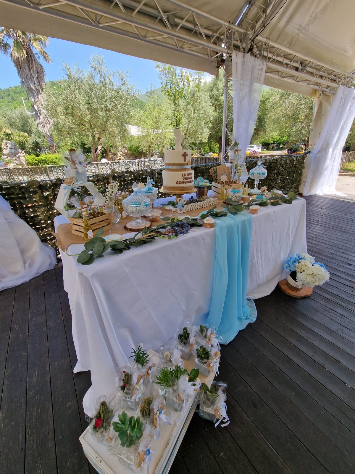 tavolo con una tovaglia bianca e una torta sopra è posto sotto una tenda