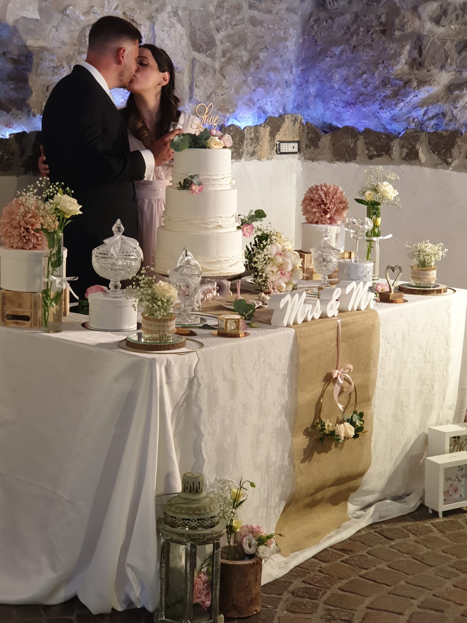 sposo e una sposa che si baciano davanti a una torta nuziale