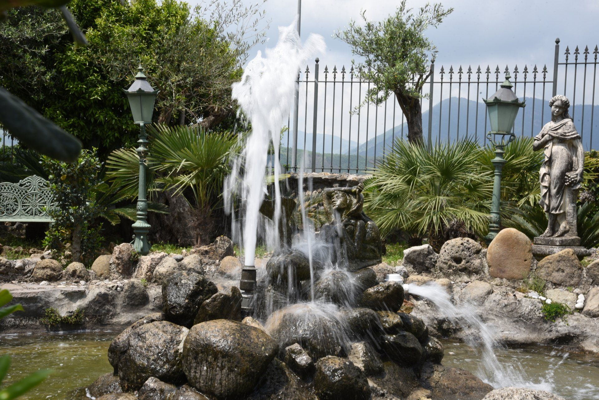 fontana in un giardino con una statua sullo sfondo