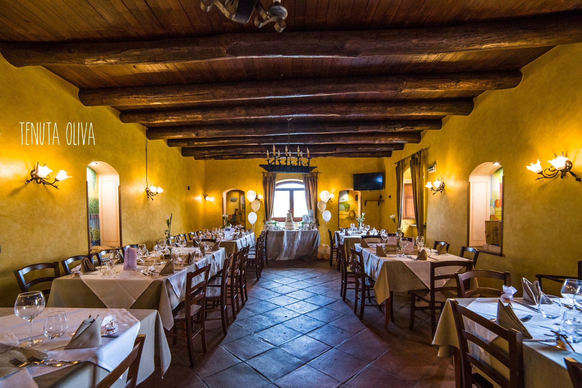 lunga sala da pranzo con tavoli e sedie e un soffitto in legno