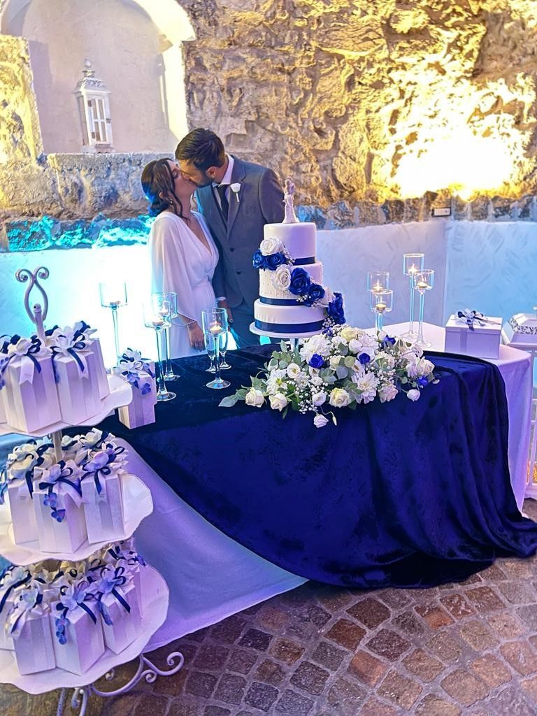 uno sposo e una sposa che si baciano davanti a una torta nuziale