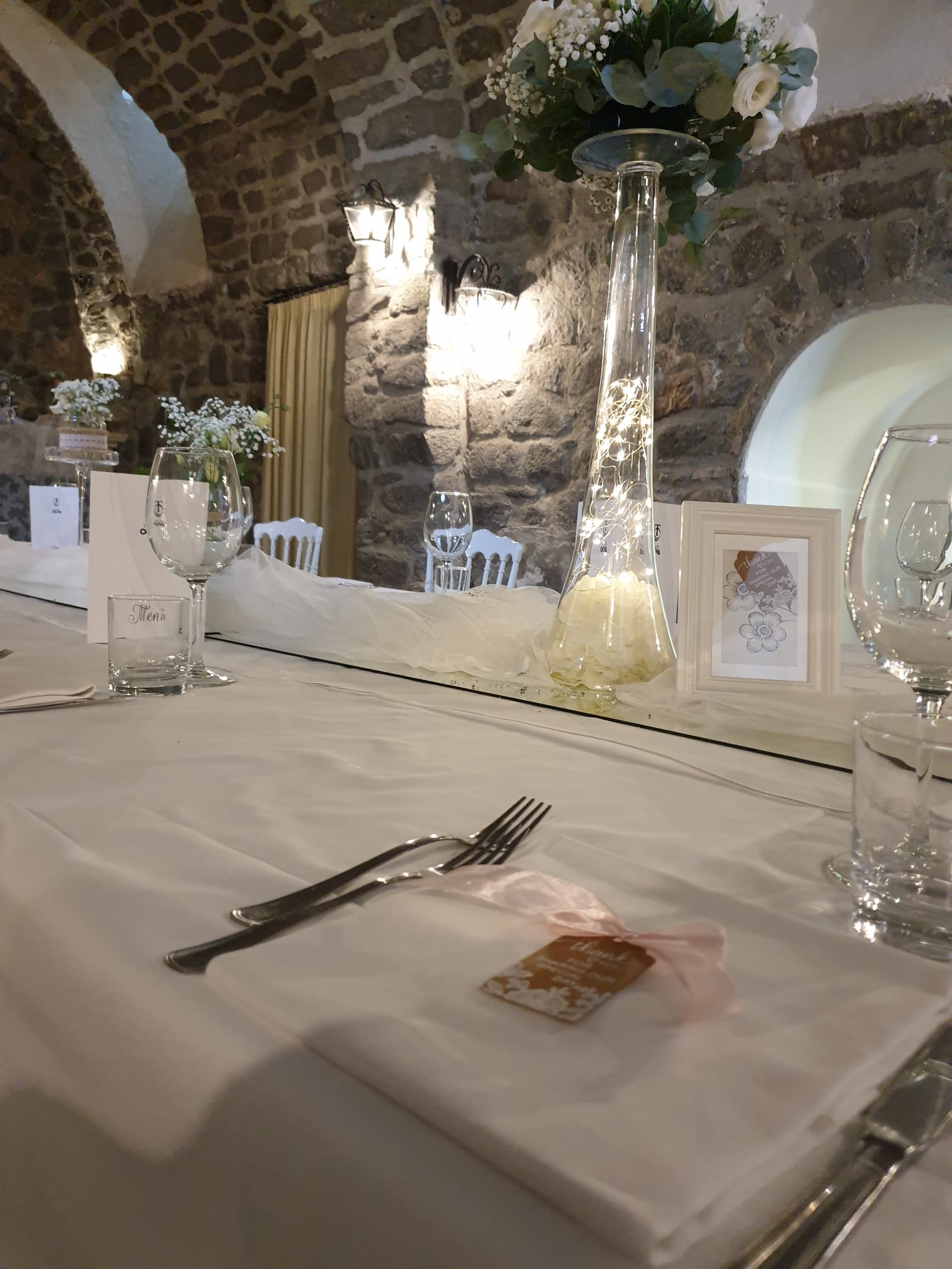 Un tavolo apparecchiato per un ricevimento di nozze con un vaso di fiori sopra.