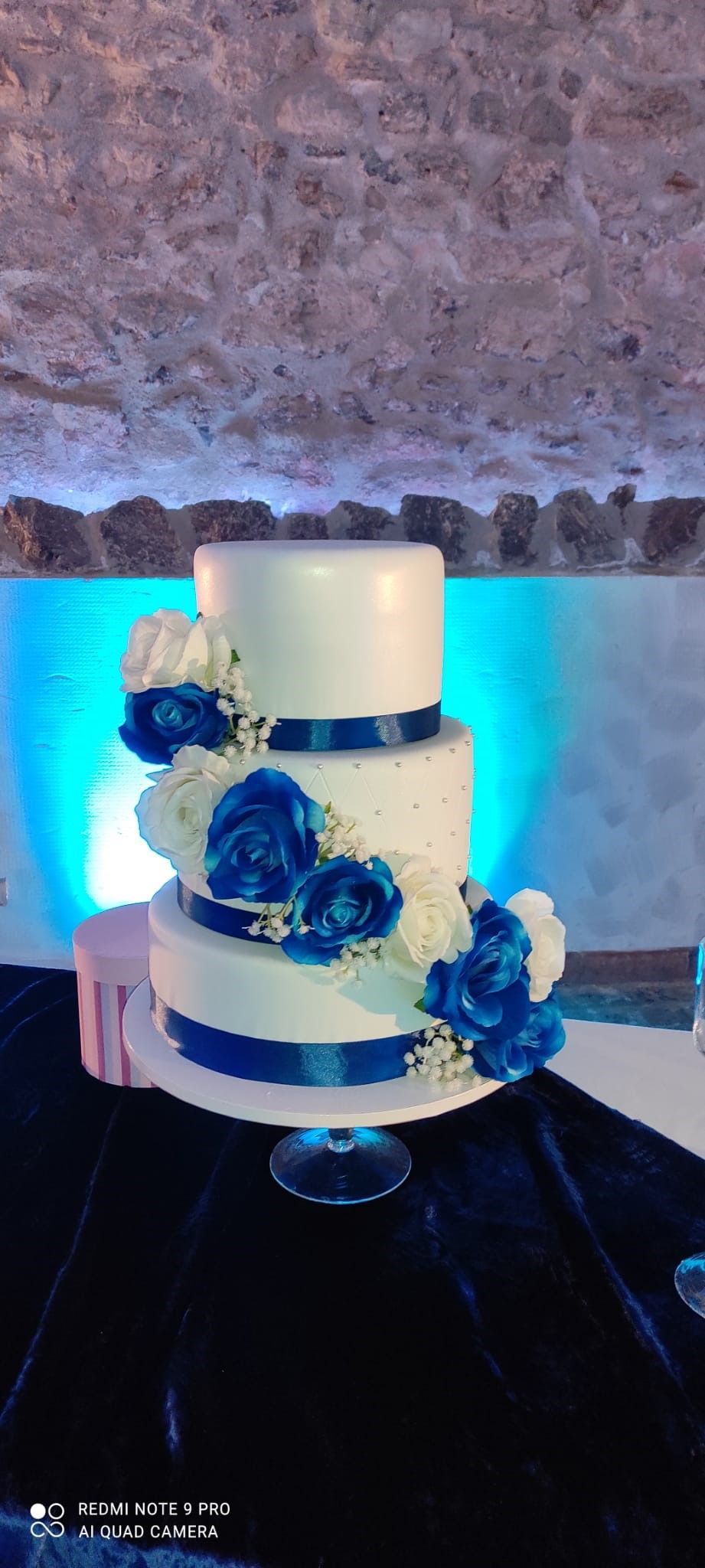 torta nuziale bianca con fiori blu è appoggiata su un tavolo