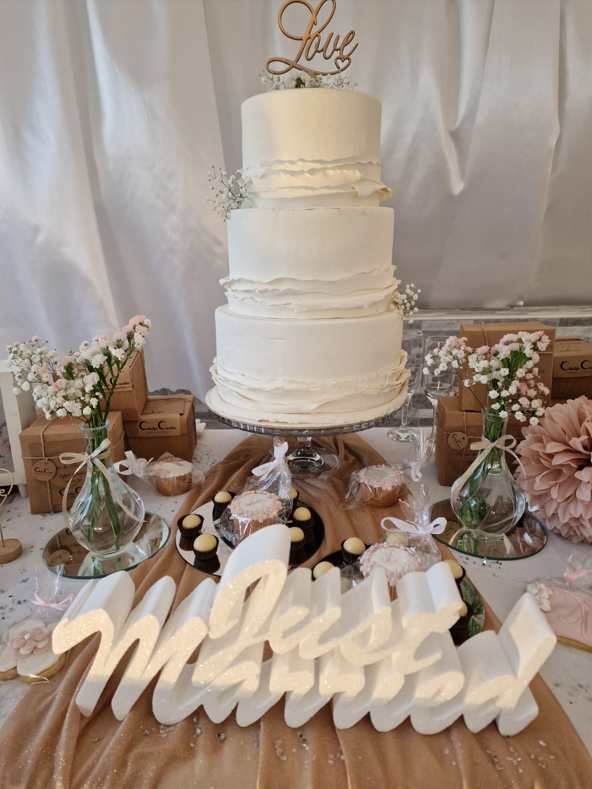 Una torta nuziale è appoggiata su un tavolo accanto a un cartello con la scritta