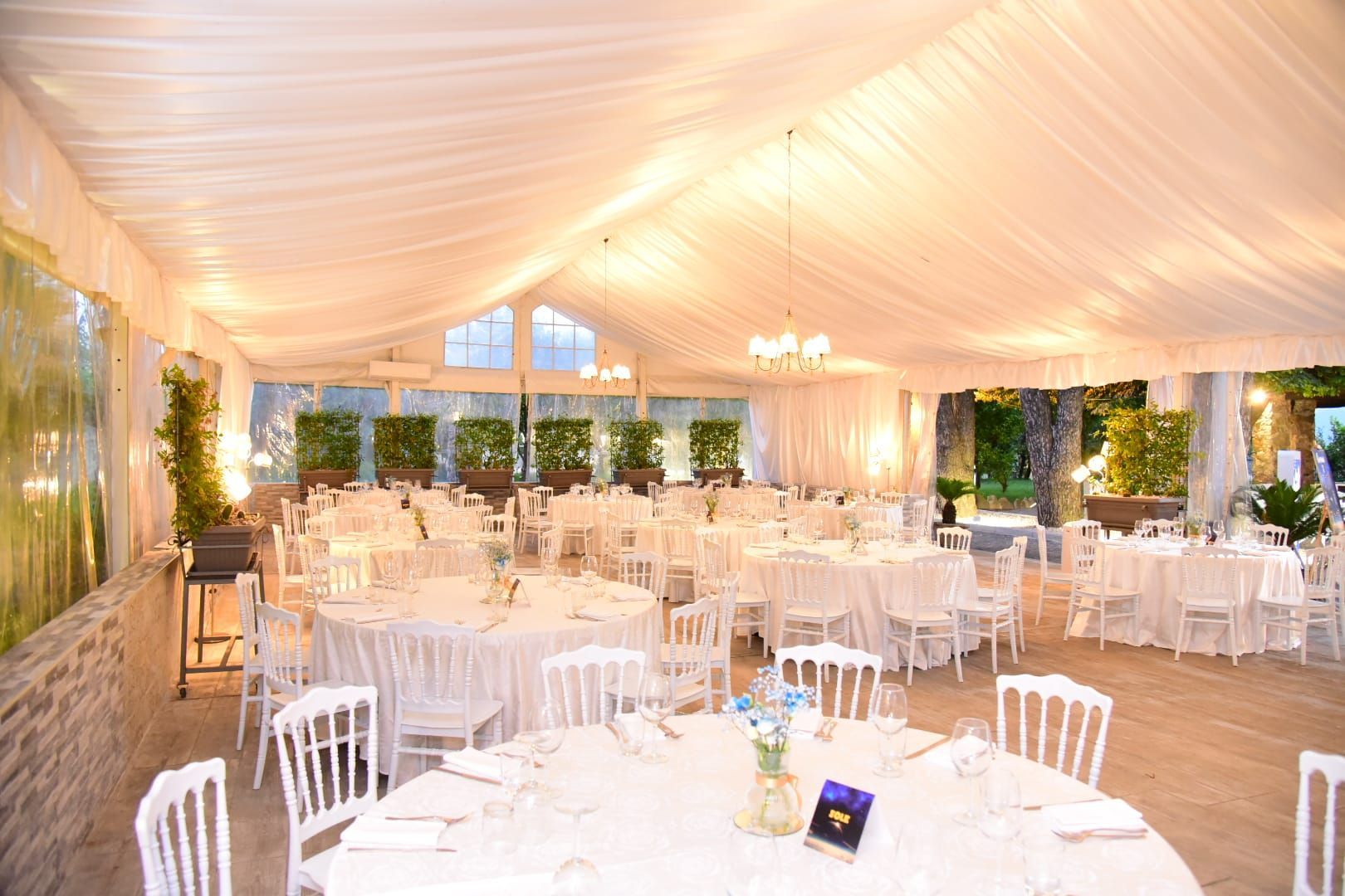 una grande stanza piena di tavoli e sedie sotto una tenda