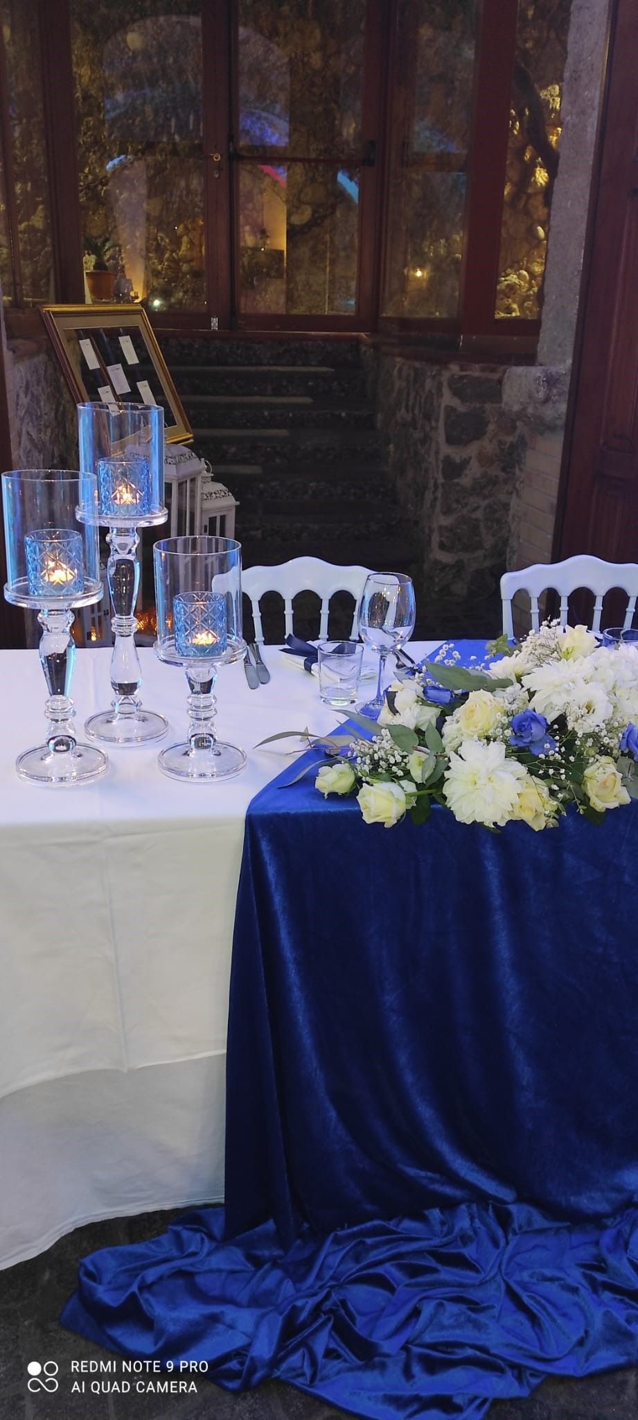 Un lungo tavolo con una tovaglia blu e dei fiori sopra