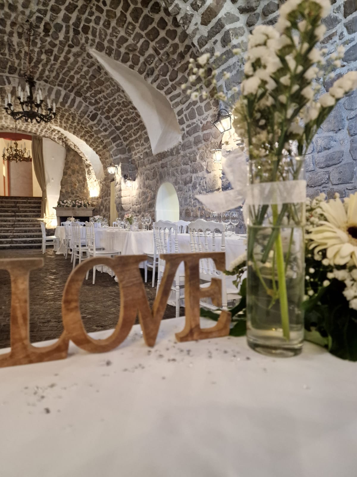 cartello appoggiato sul tavolo  di un ristorante accanto a un vaso di fiori