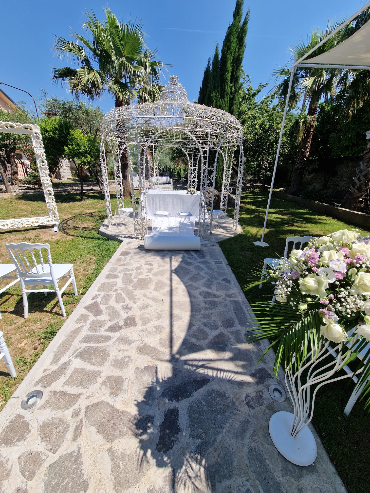 sentiero in pietra che conduce a un gazebo con sedie e fiori