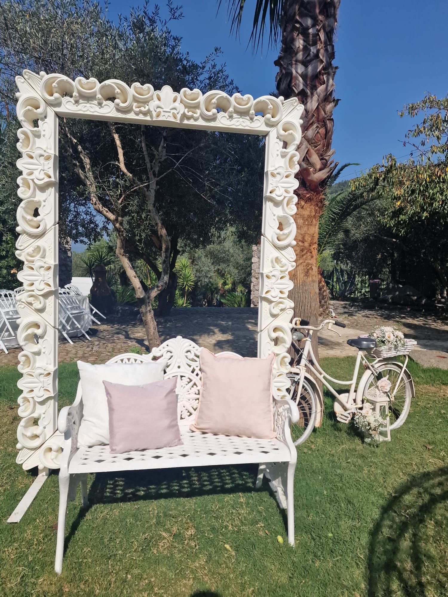 Una bicicletta bianca è parcheggiata accanto a una panchina bianca con dei cuscini.
