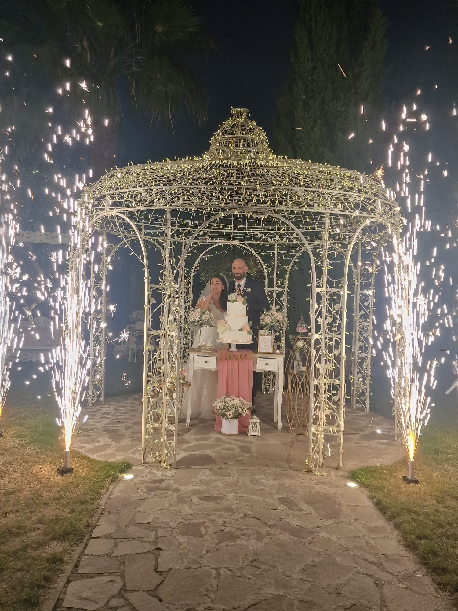 sposi tagliano la torta nuziale sotto un gazebo