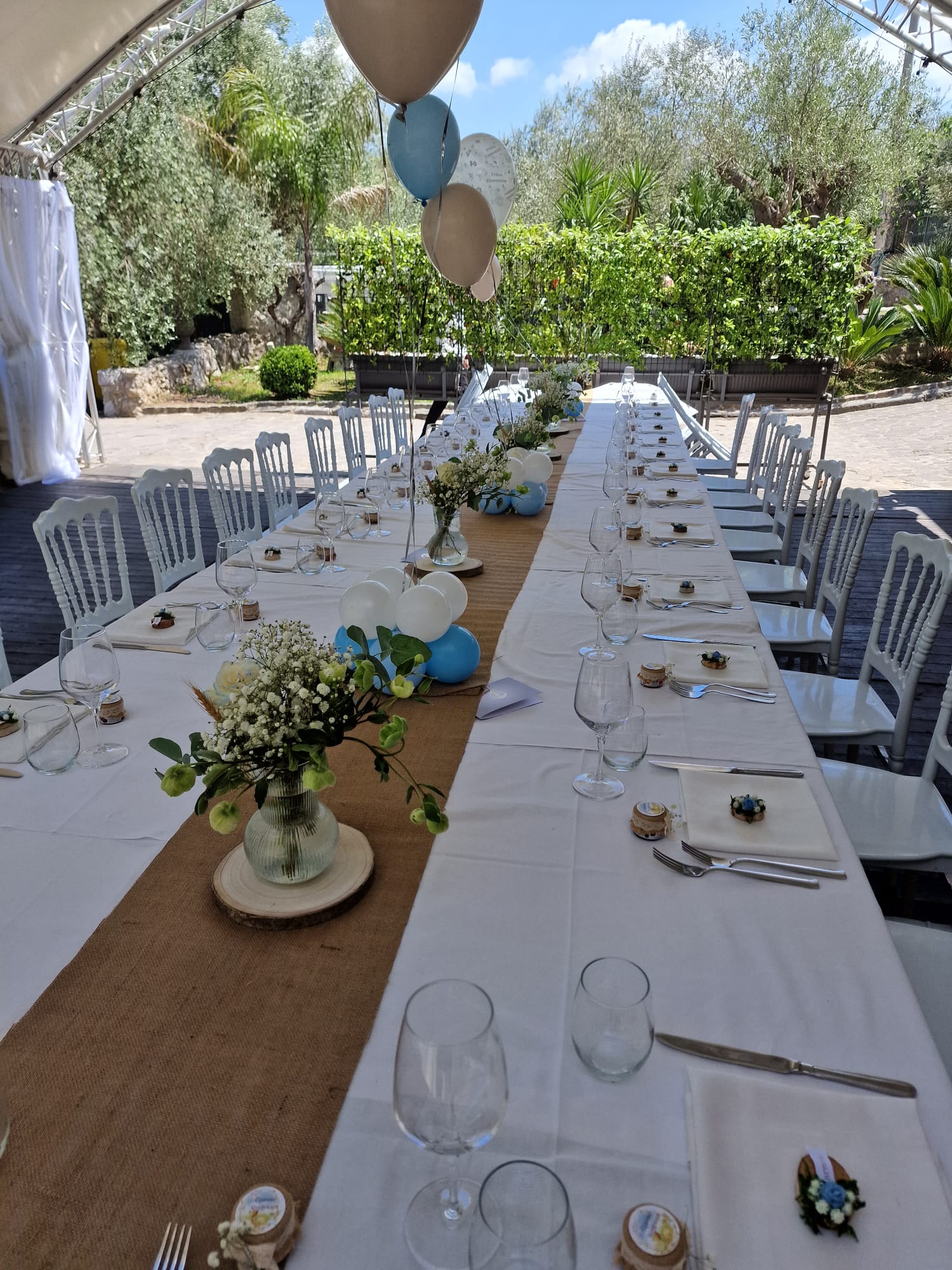 lungo tavolo con sopra un vaso di fiori e palloncini