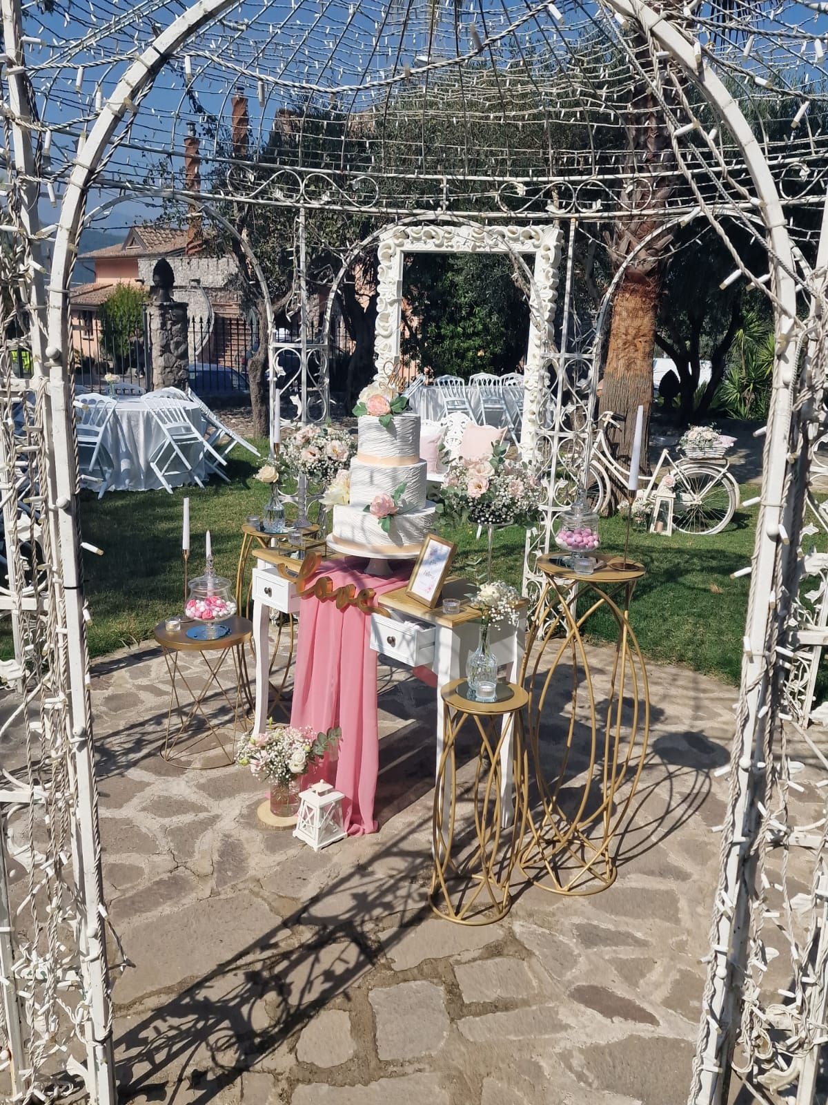 tavolo con una torta sopra sotto un arco bianco