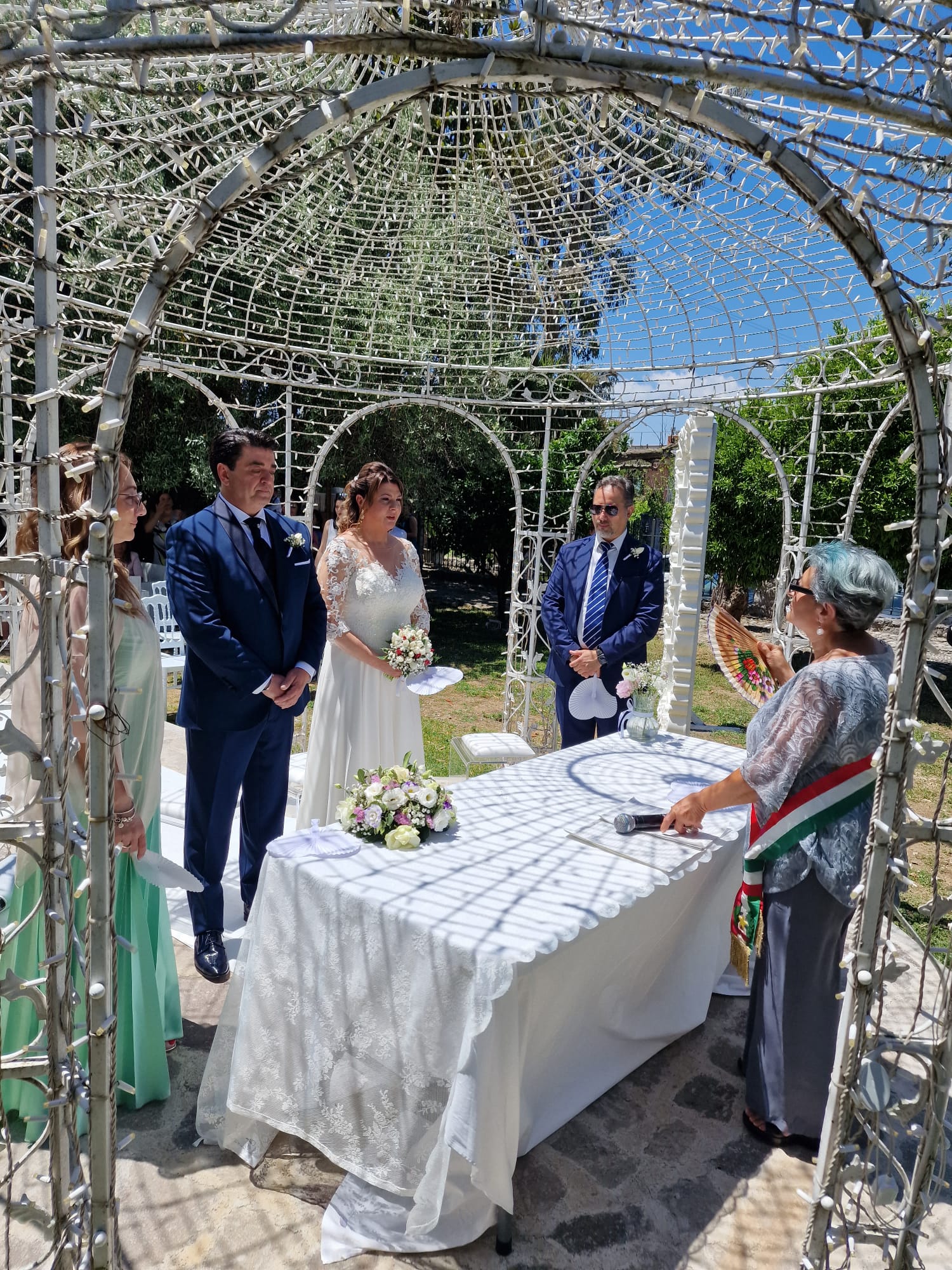 Gli sposi sono in piedi davanti a un tavolo durante una cerimonia nuziale.