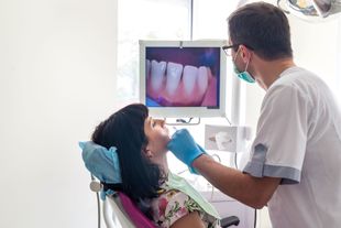 A dentist from Paulson Dental performing an oral exam on a woman during a general dentistry visit in Sioux Falls, SD.] 