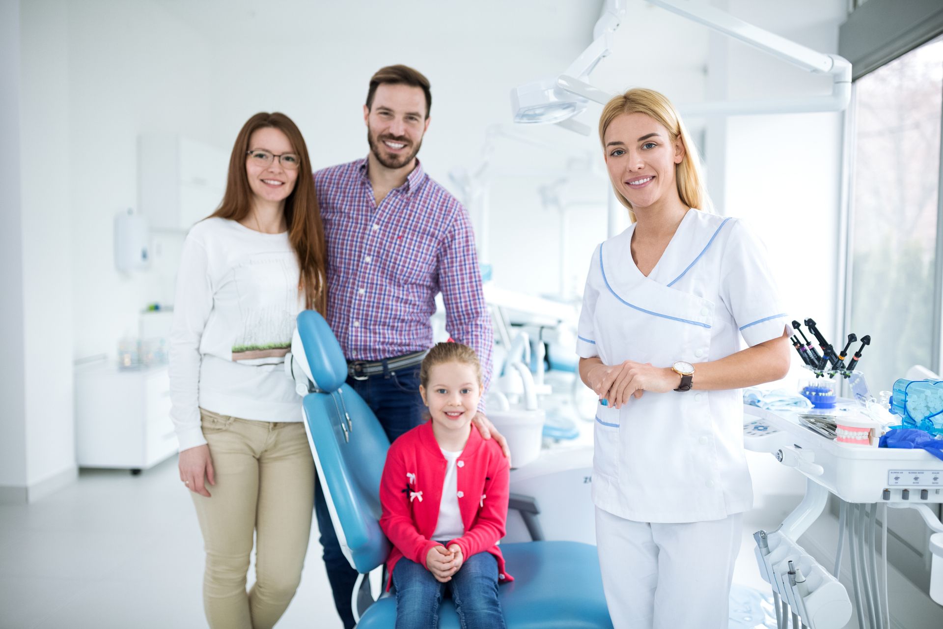 Smiling family with a friendly young dentist at a bright, welcoming dental office.