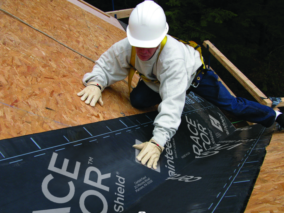 A man wearing a hard hat is working on a roof