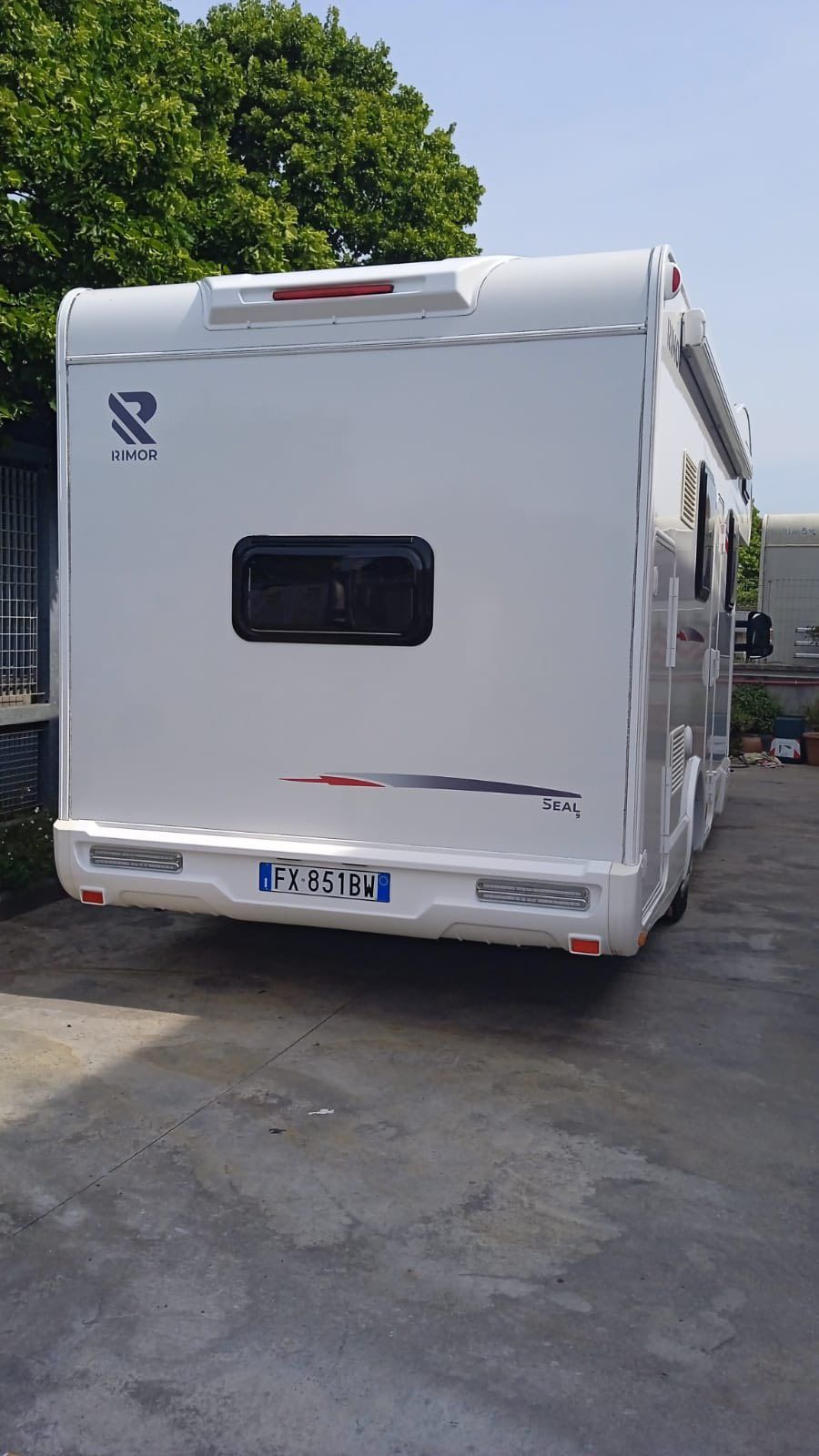 Vista posteriore di un camper bianco parcheggiato all'esterno con targa visibile.