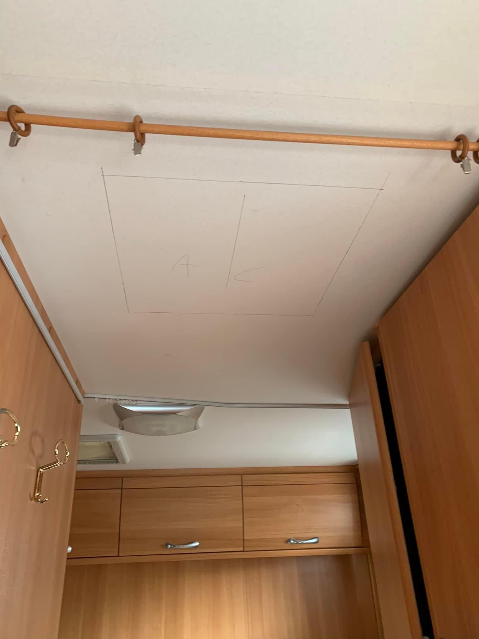 Vista interna del soffitto di un camper, con sportello, asta di legno e armadietti.