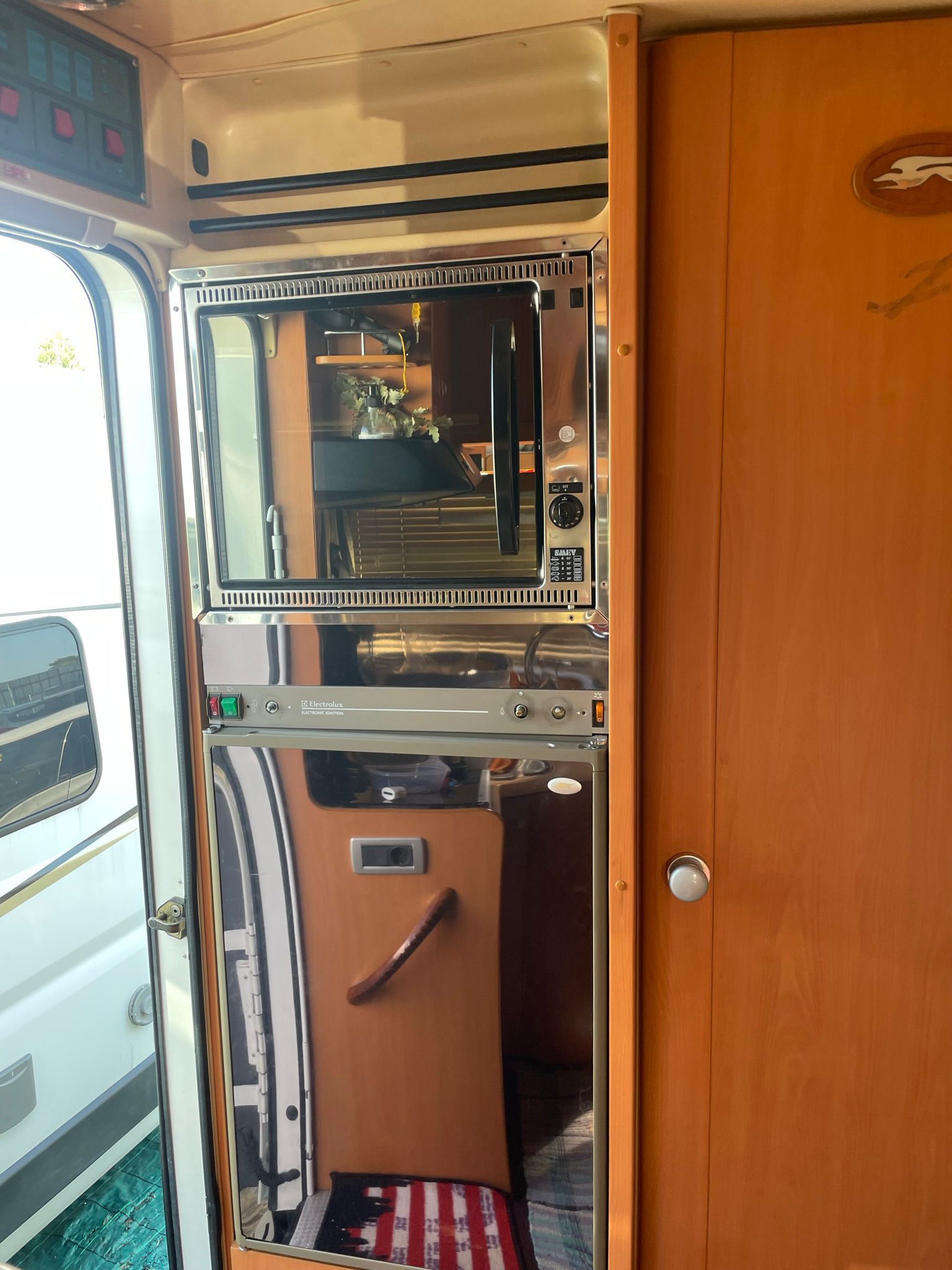 Interno di un camper dotato di microonde, forno e mobili in legno.