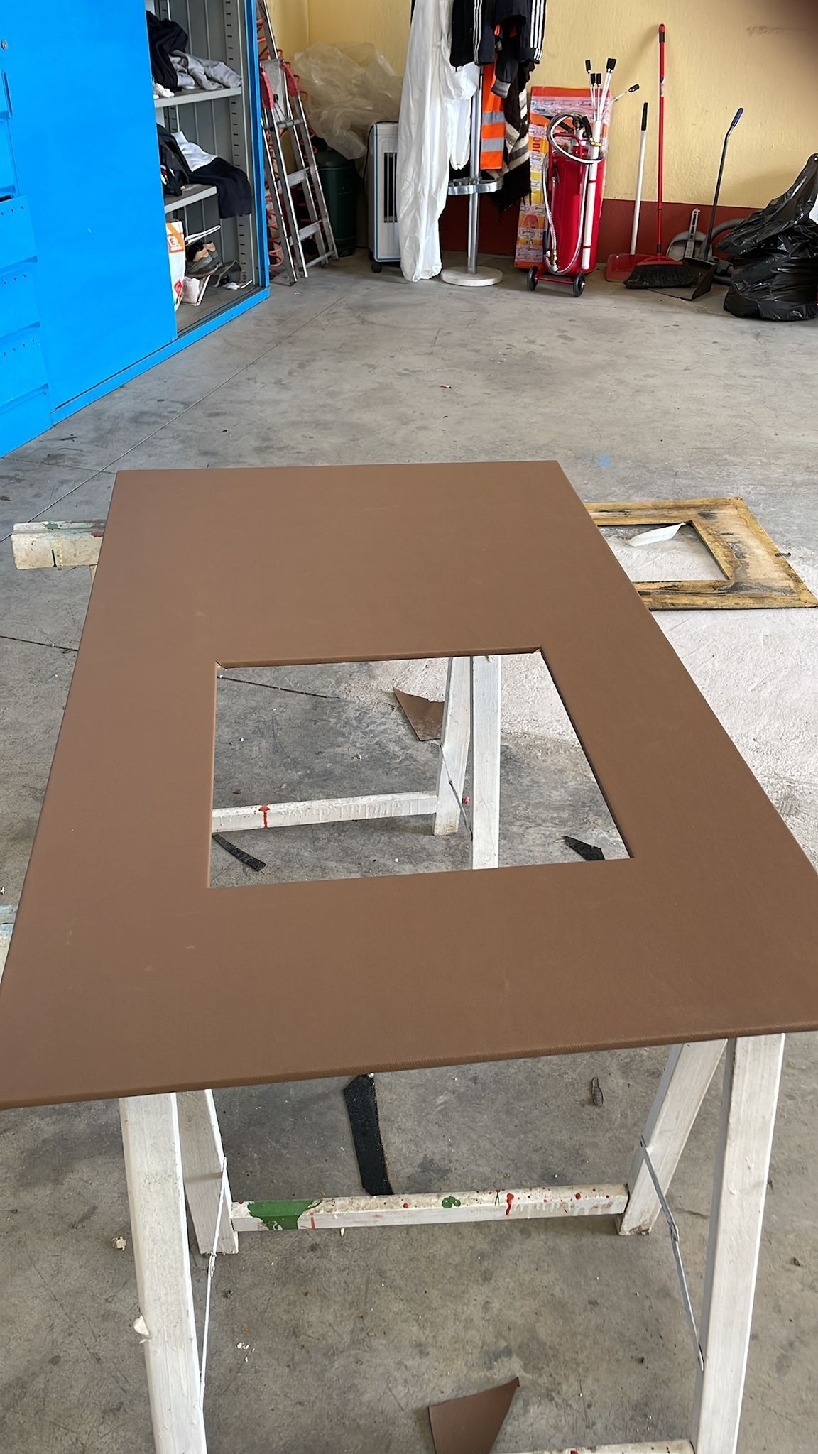 Pannello rettangolare marrone con un ritaglio quadrato su un cavalletto bianco.