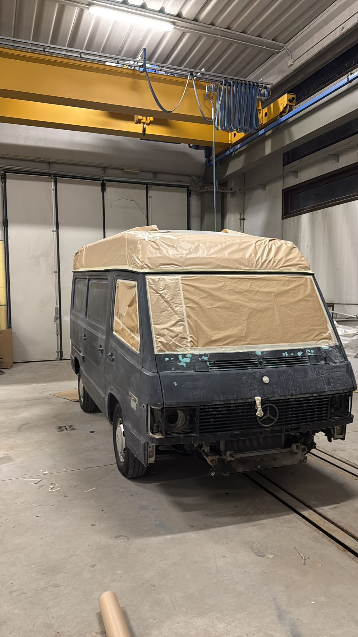 Furgone ricoperto di carta marrone, pronto per essere verniciato in officina.