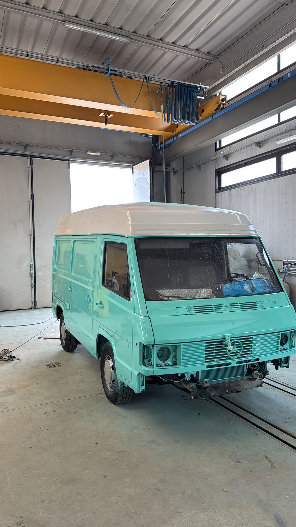 Furgone color acqua in garage, tetto beige, in fase di restauro.