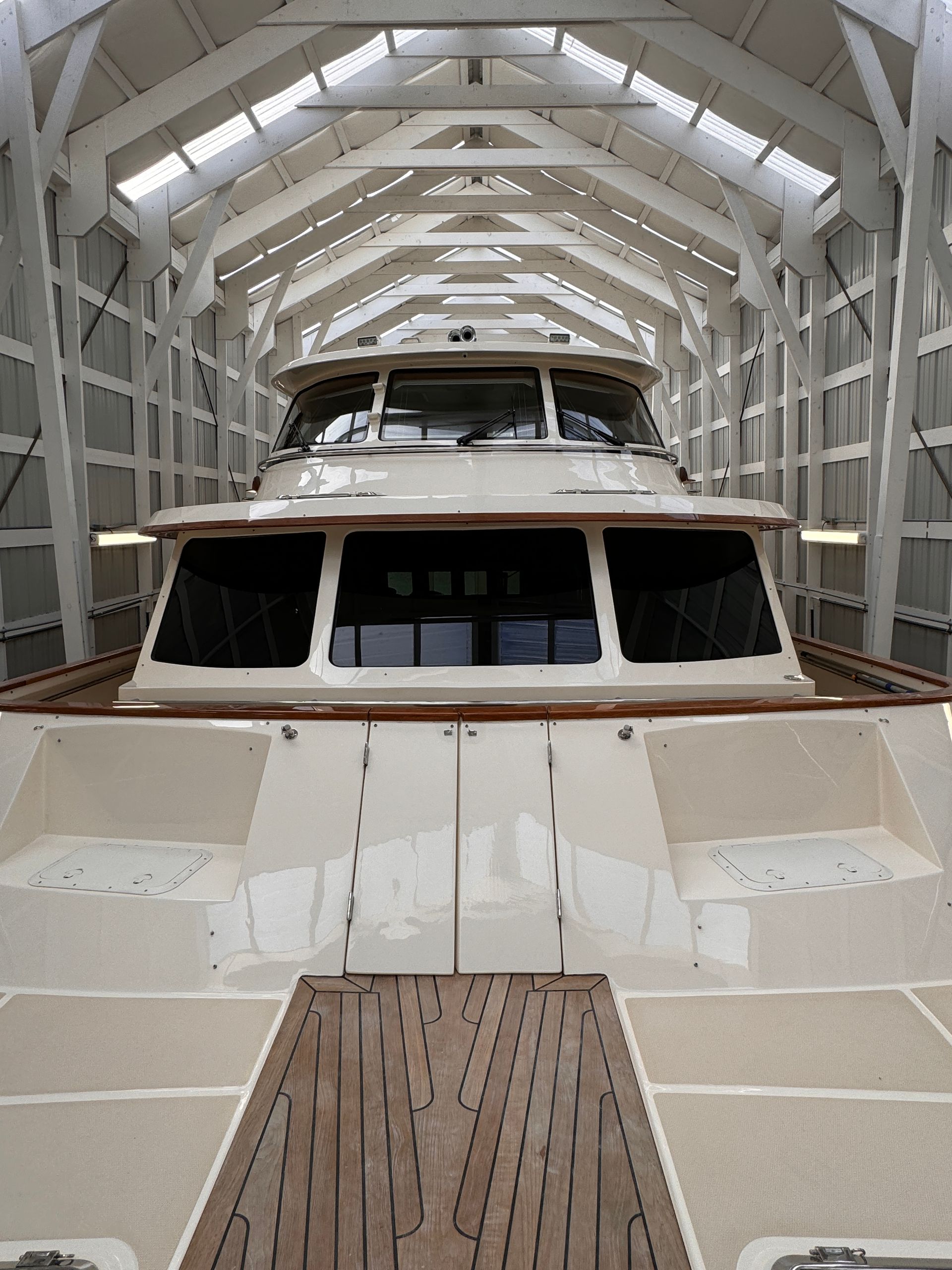 A boat is sitting inside of a building with a wooden deck.