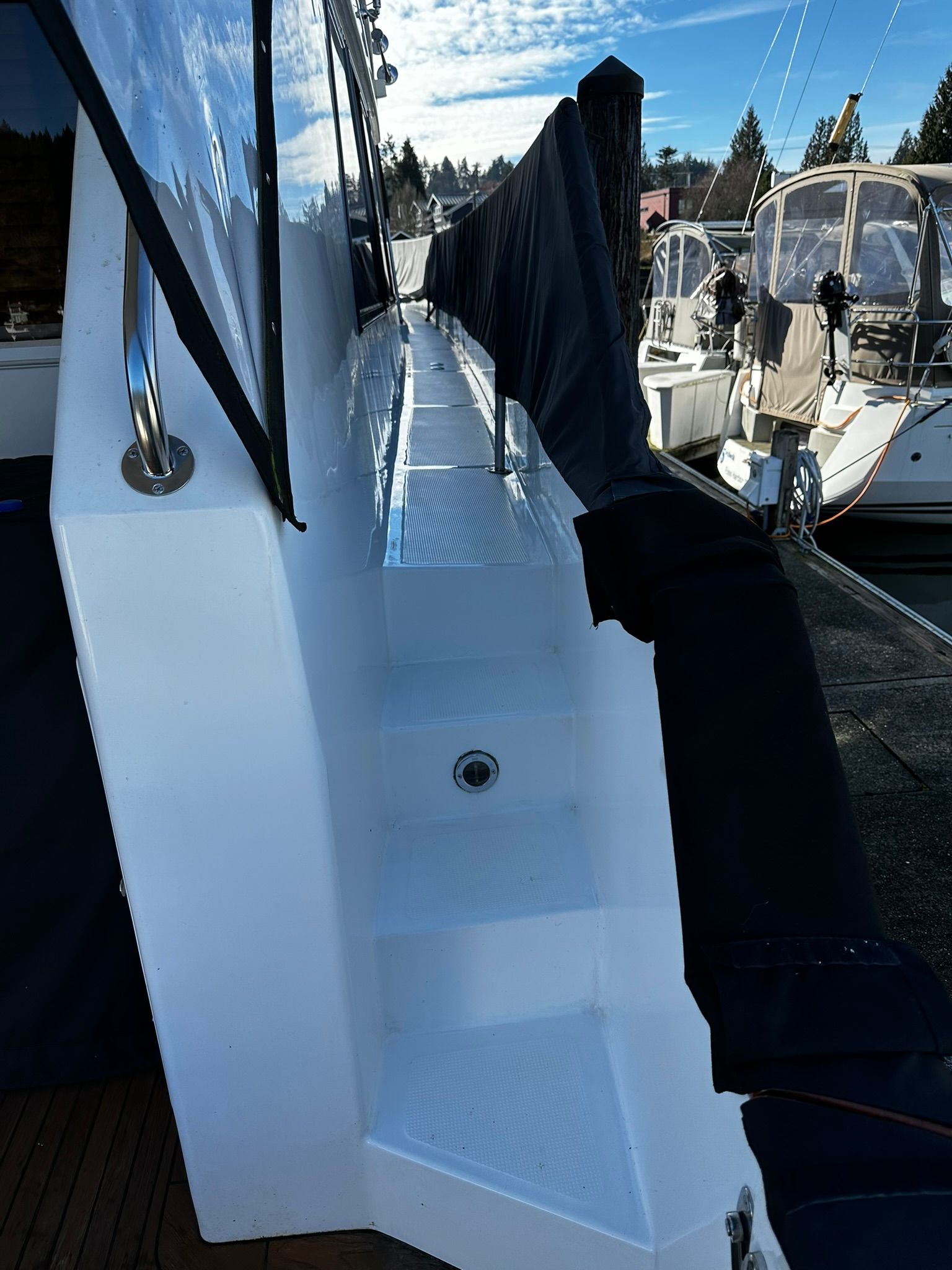 A boat with stairs leading up to it is docked in a marina.