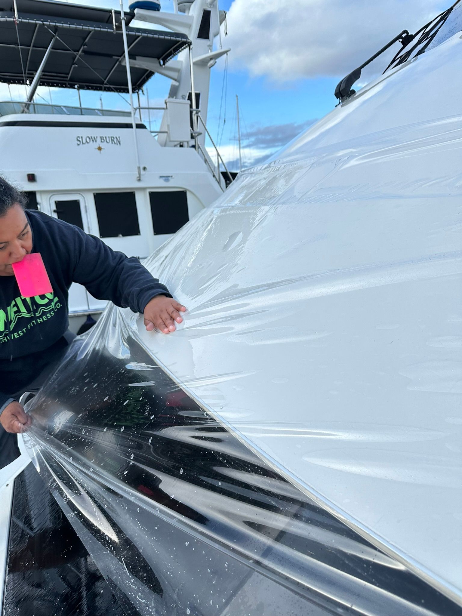 A woman is wrapping a boat in plastic wrap.