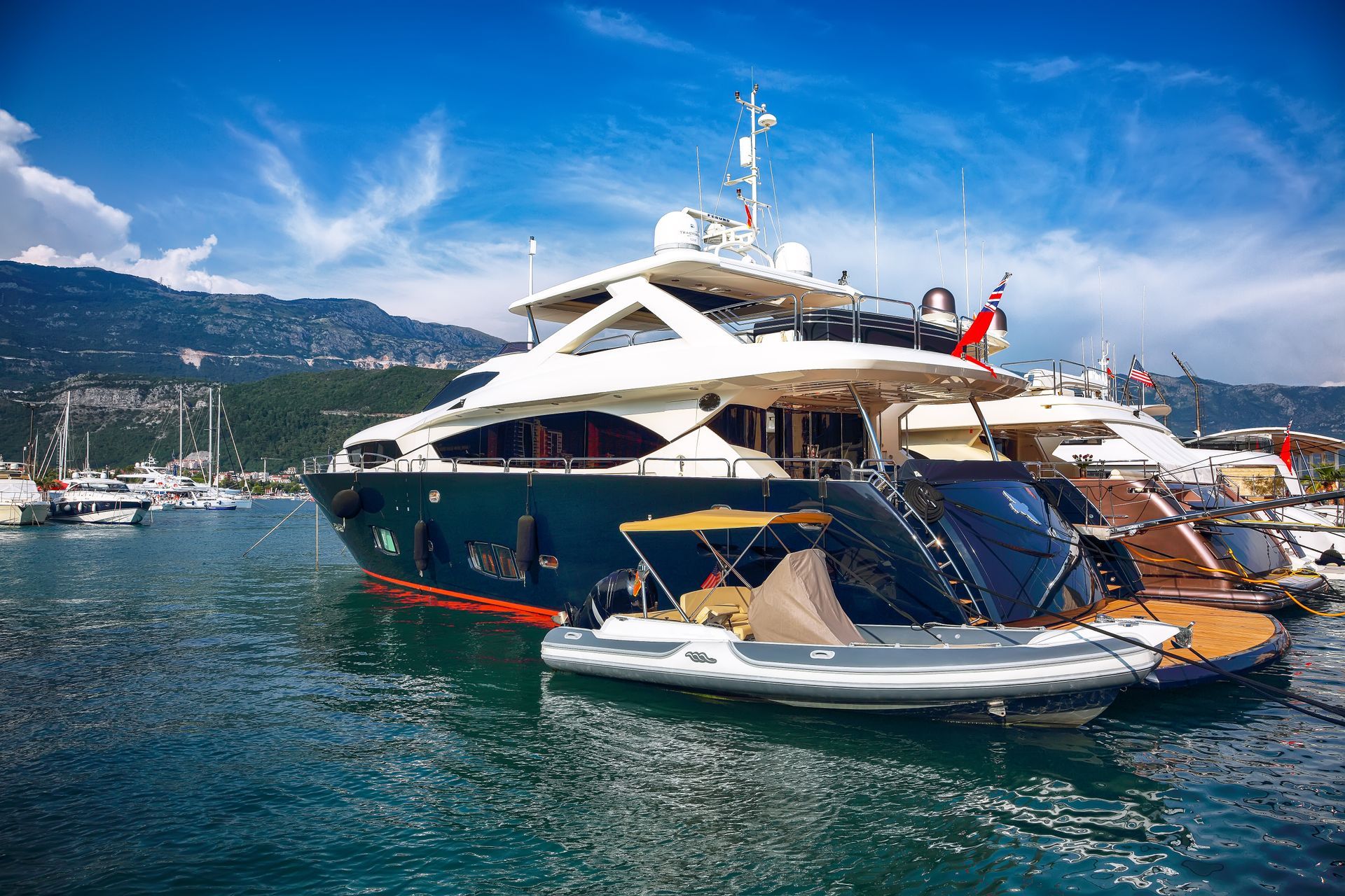 A large yacht is docked in a harbor next to a smaller yacht.