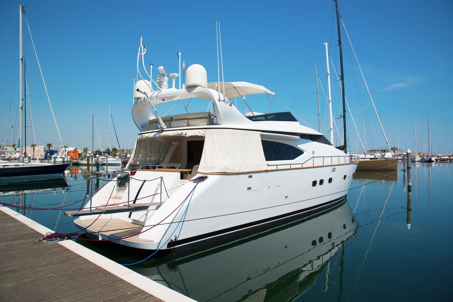 A large white yacht is docked in a marina.