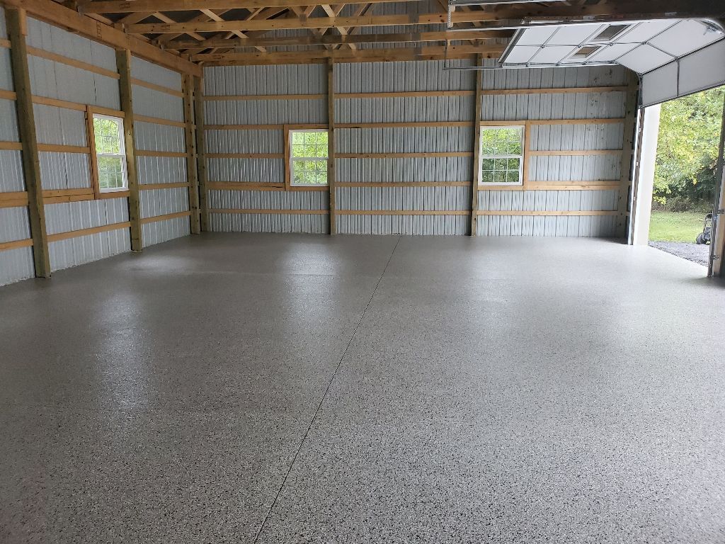 Interior of a new, empty garage with concrete floor, wood framing, and three windows.