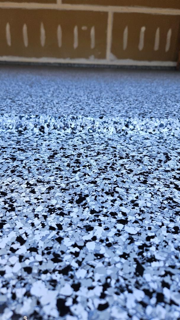 Epoxy garage floor with blue, gray, and black flakes, close-up view.