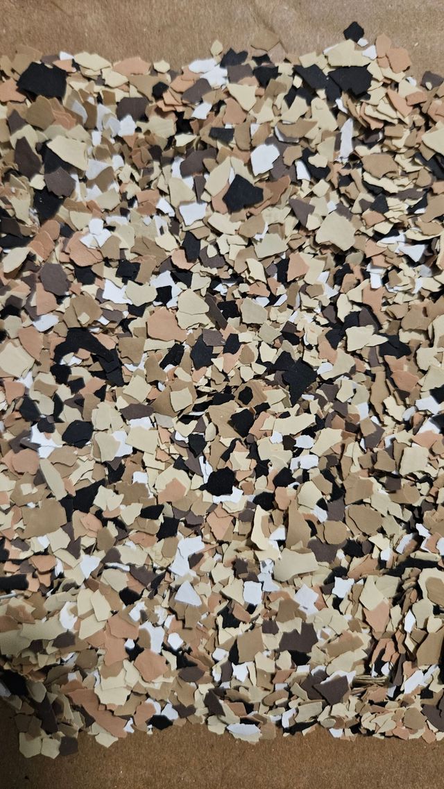 Multi-colored floor flakes in shades of beige, black, brown, and white.