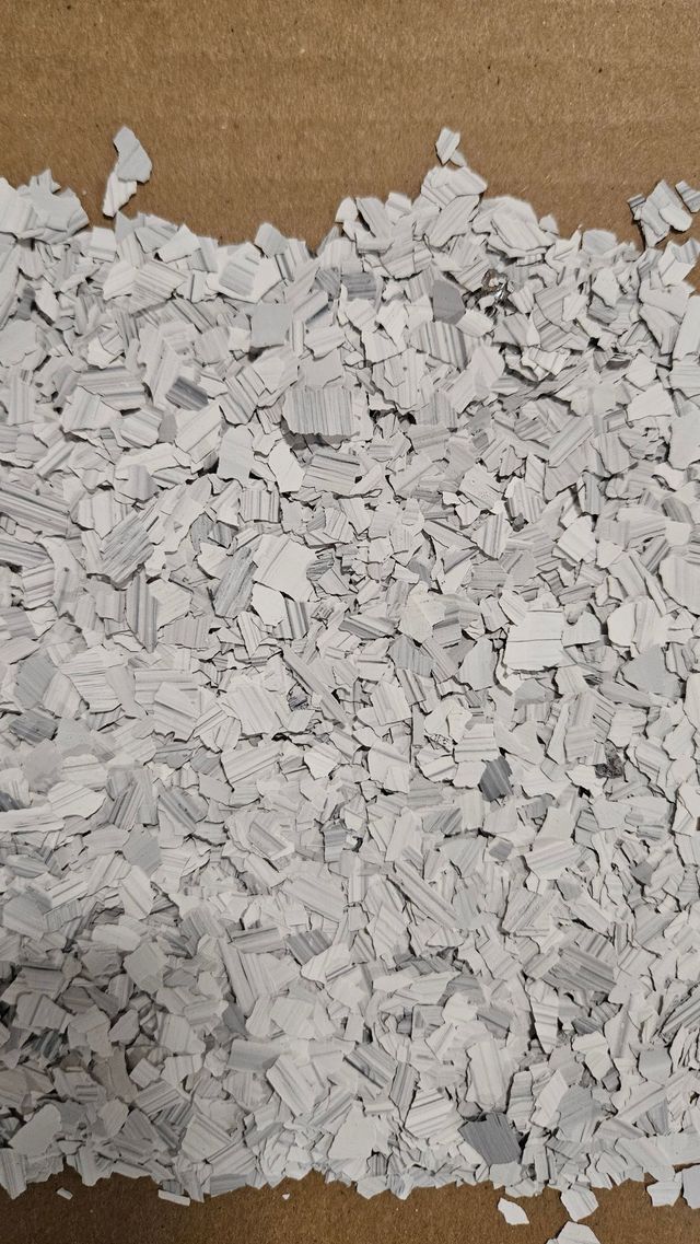 Gray and white floor flakes scattered on a brown surface.